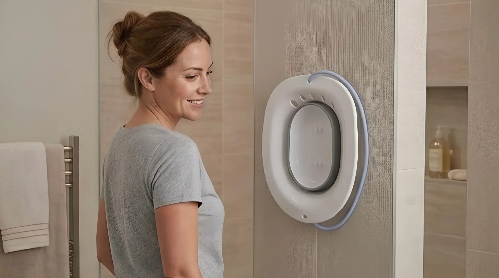 Donna in un bagno luminoso accanto al bidet portatile AquaNési